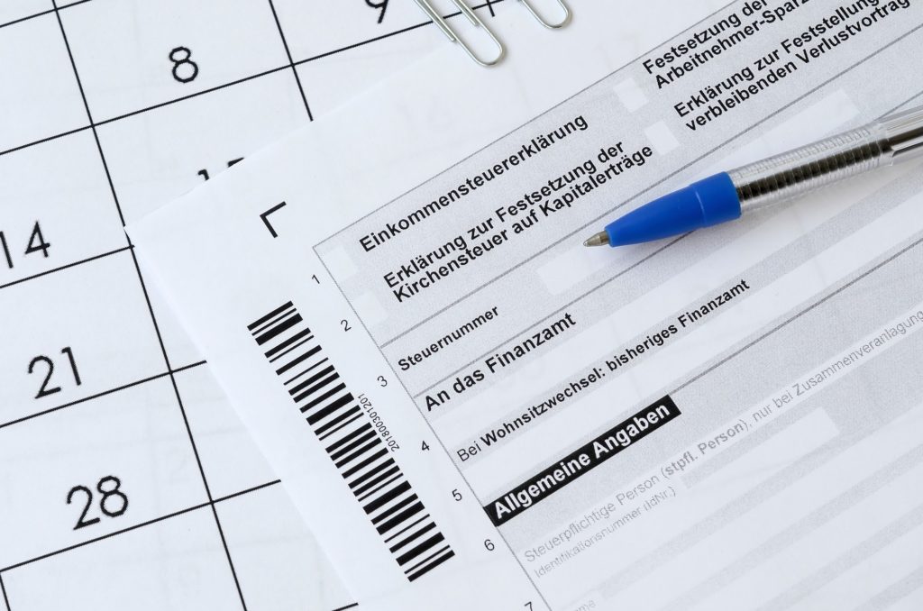 German tax form with pen lies on office calendar. Concept of annual tax paying in Germany